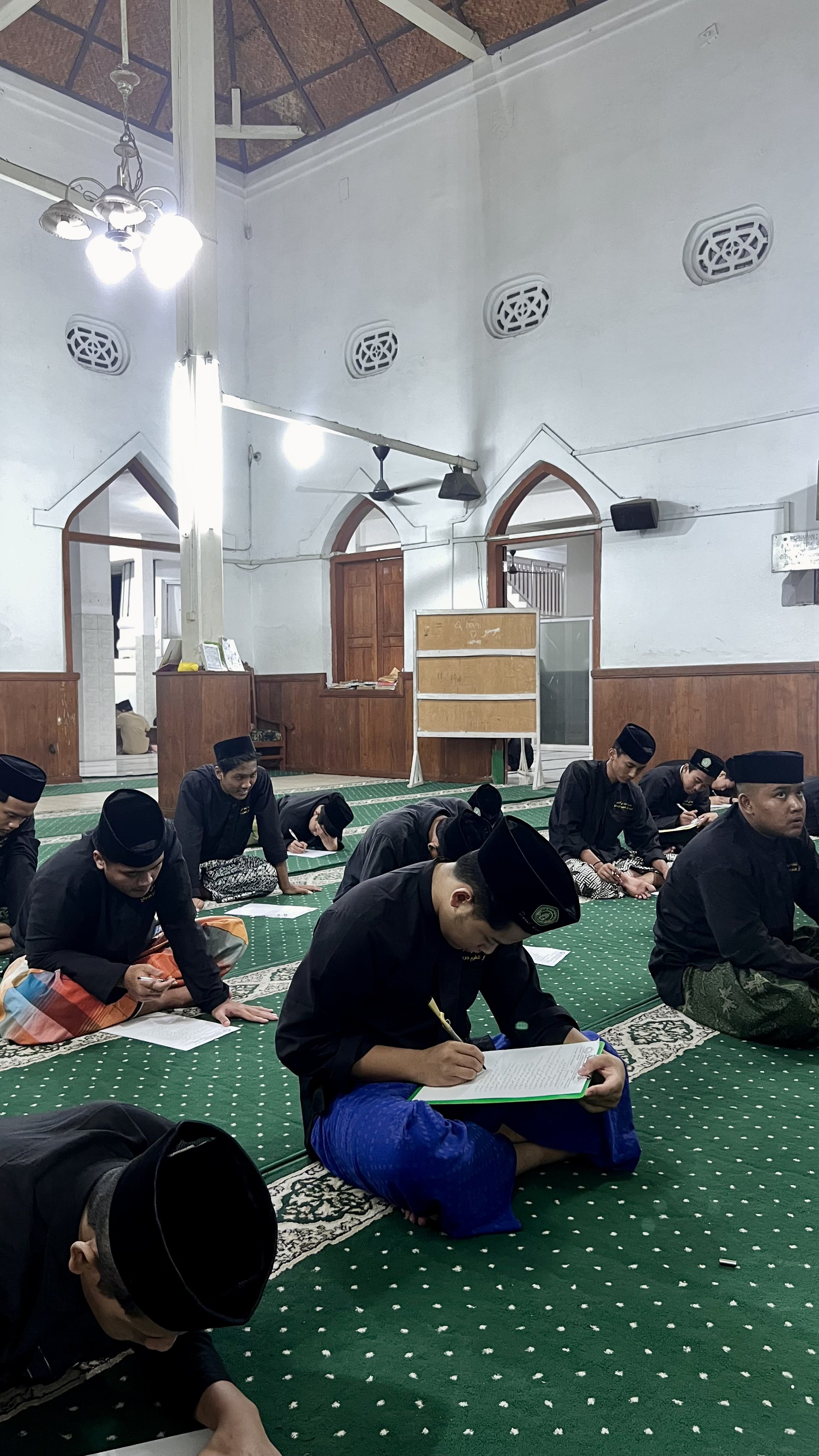 Santri Menulis Lembar Jawaban dan Catatan Kitab di Masjid